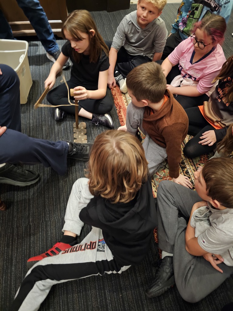 student trying a native american tool while other students watch