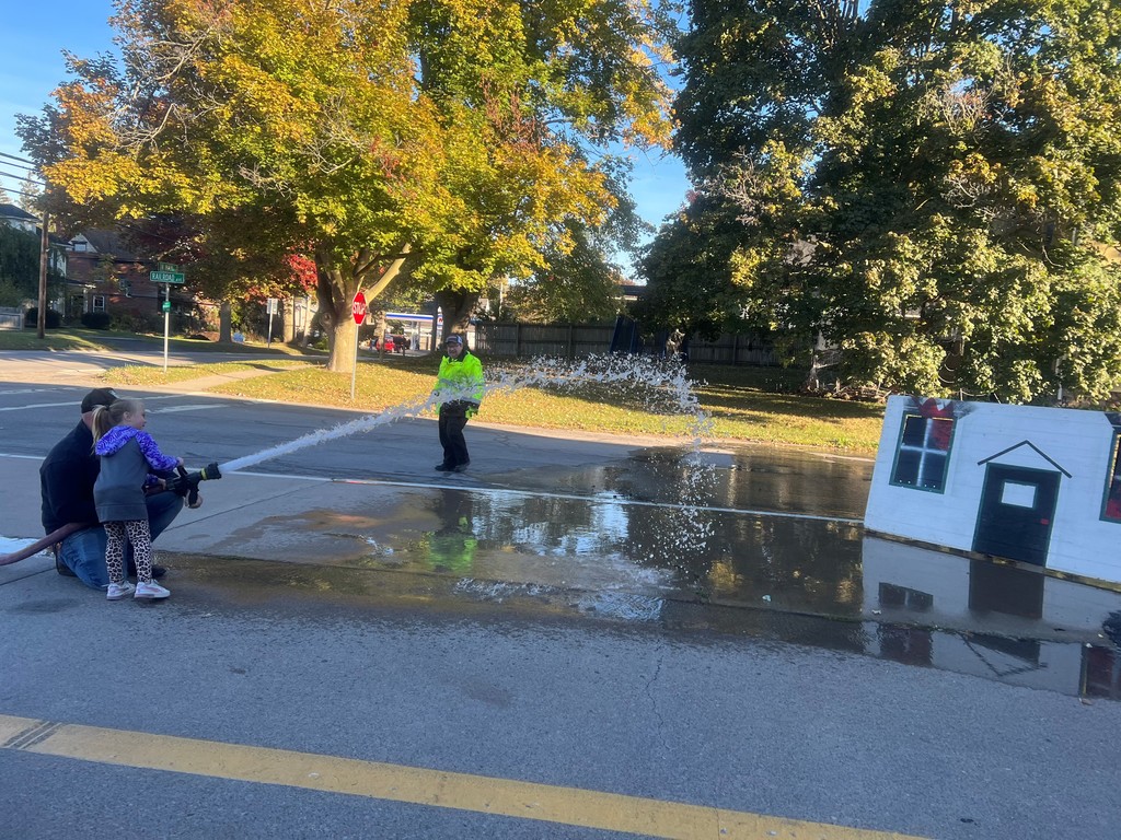 student spraying hose with adult