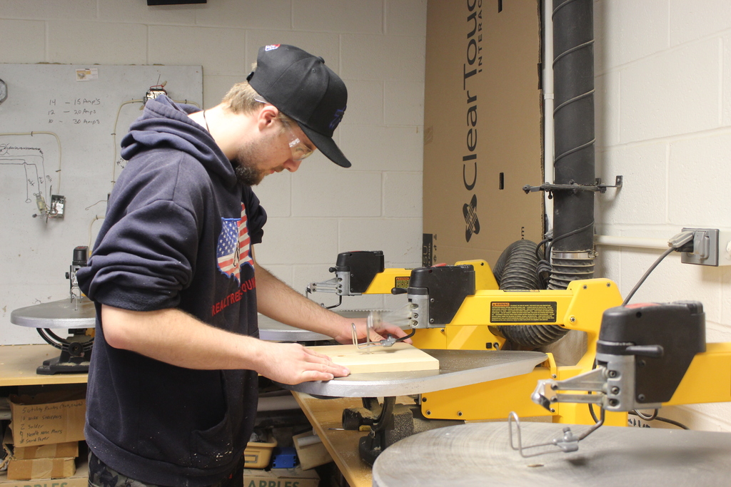boy using jigsaw on a piece of wood