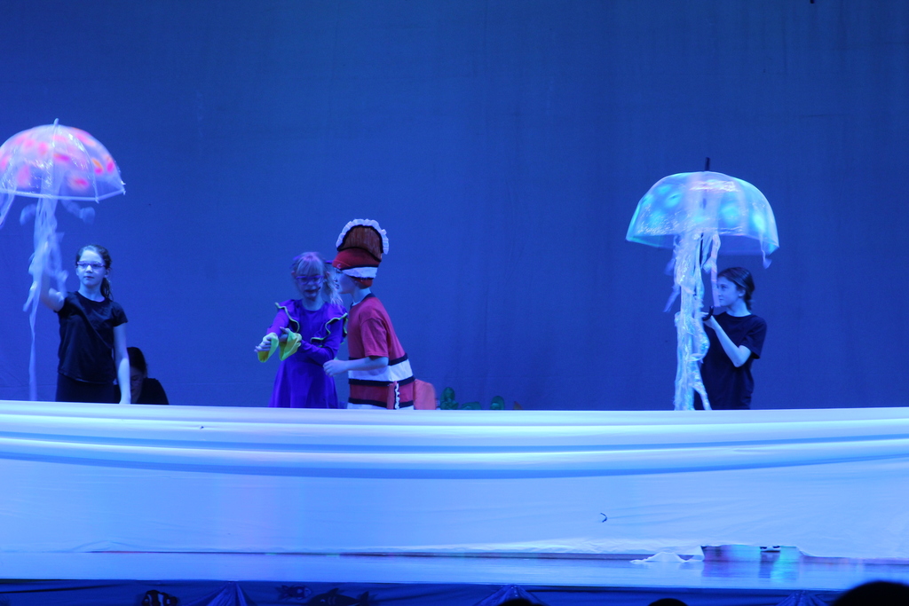 four students acting on stage in costumes