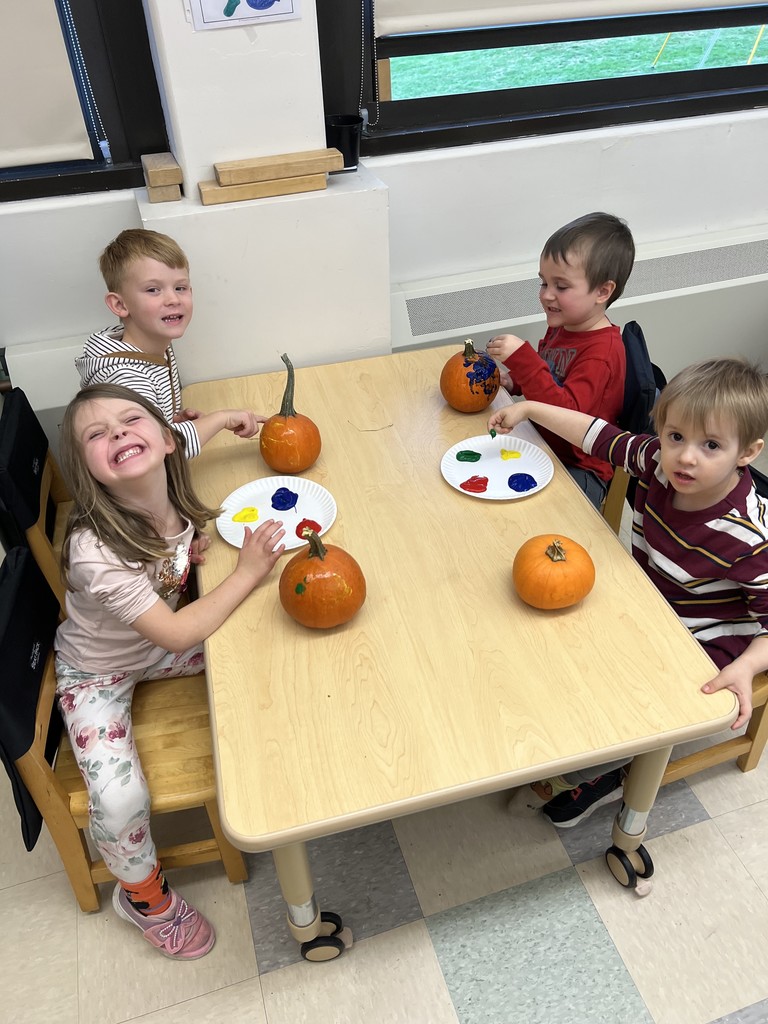 students seated at table painting their pumpkins