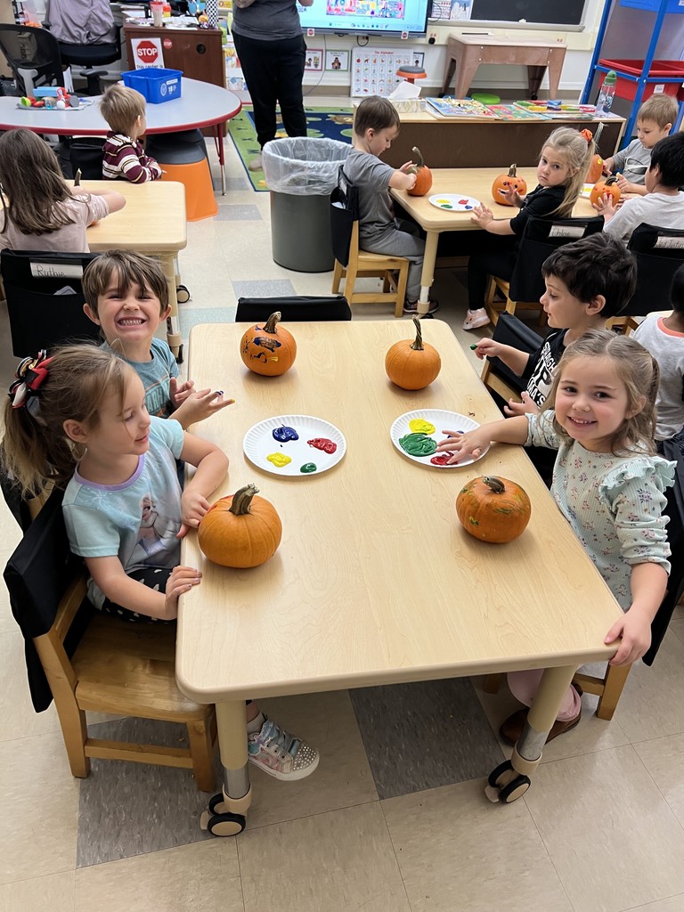 students seated at table painting their pumpkins