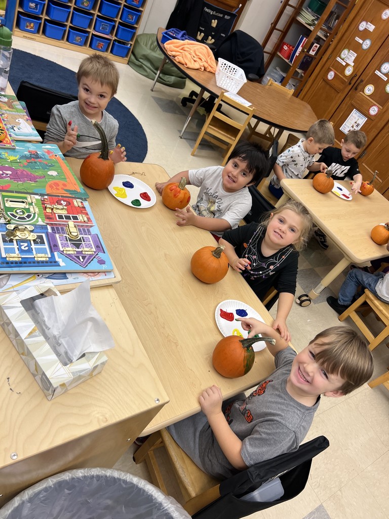 students seated at table painting their pumpkins