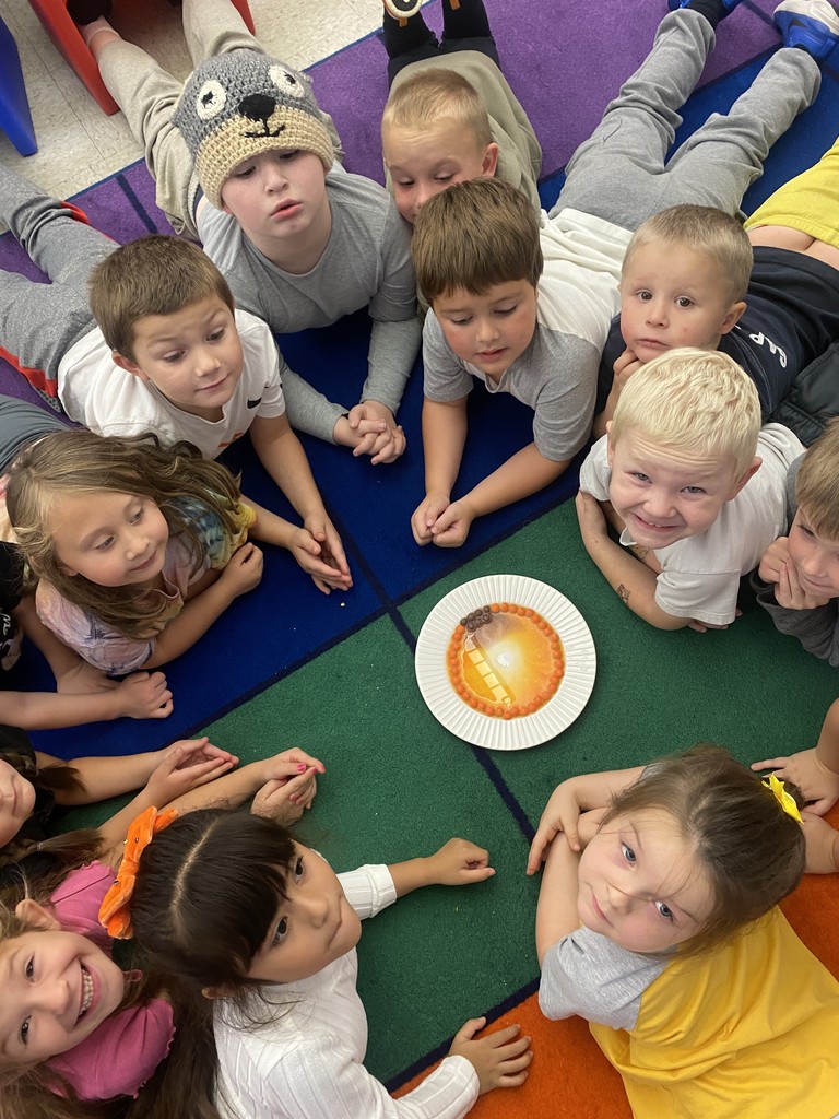 students lying on rug looking at experiment
