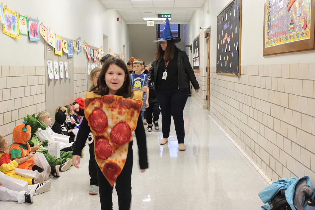 students in costumes walking through the hallway with staff
