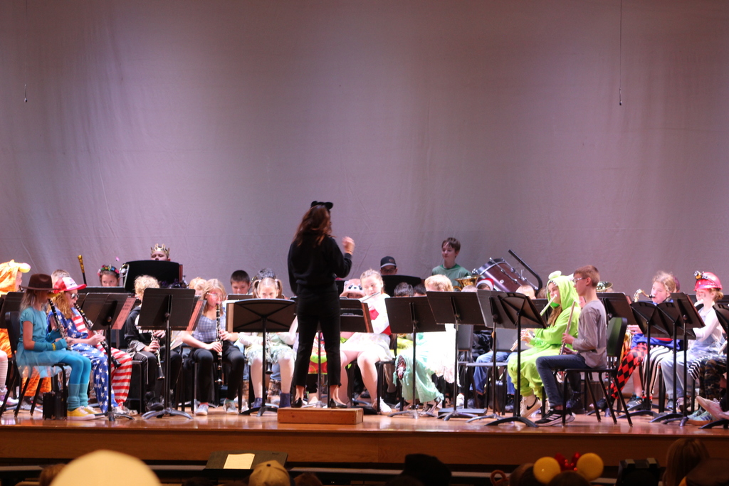 students playing in band on stage led by music teacher