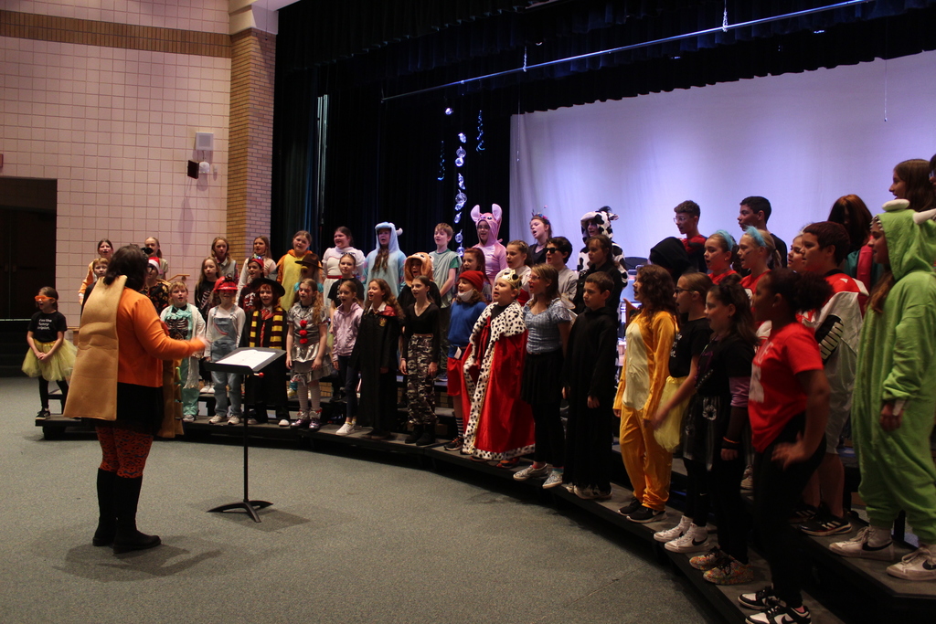 students on risers singing in choir led by music teacher