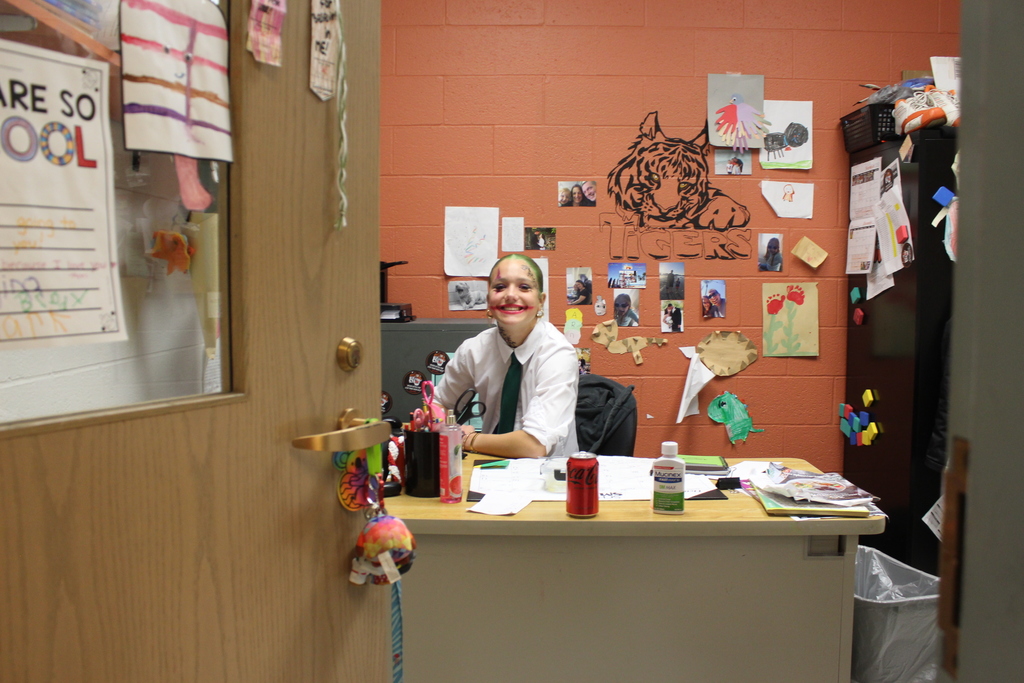 girl dressed in Halloween costume behind teacher desk in office
