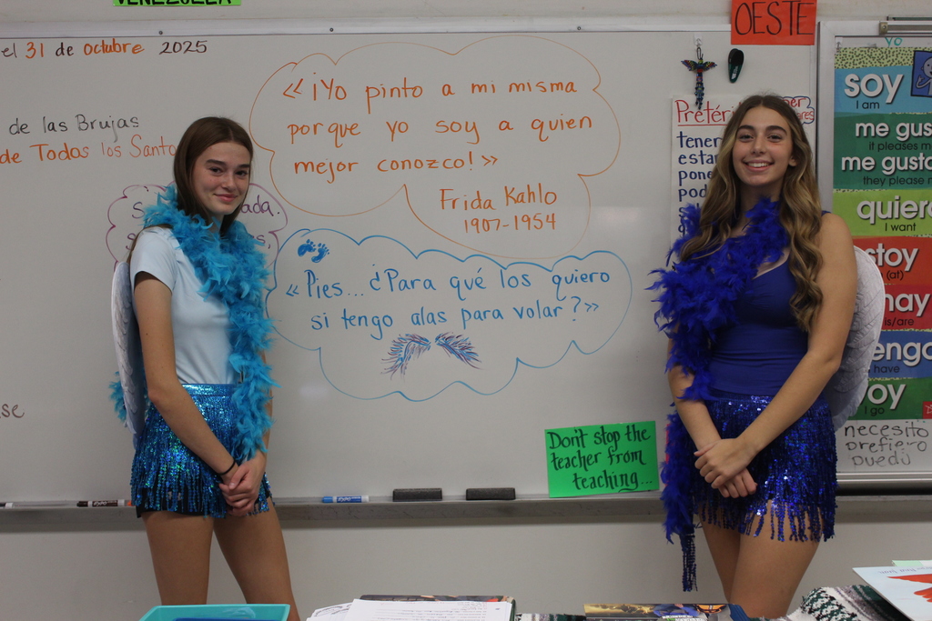 two students dressed as angels in front of the board