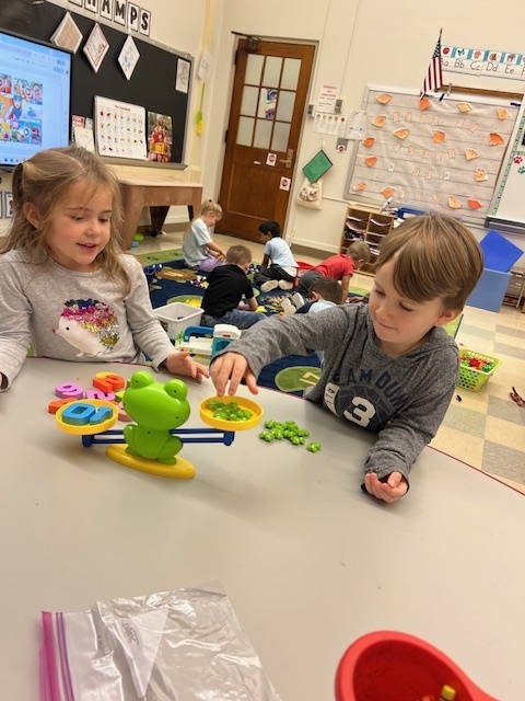 two students sitting at table manipulating objects in front of them