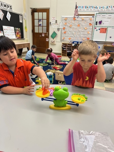 two students sitting at table manipulating objects in front of them