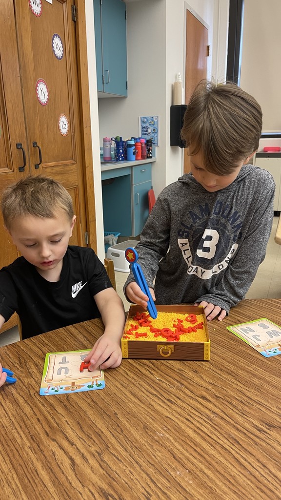 two students sitting at table manipulating objects in front of them