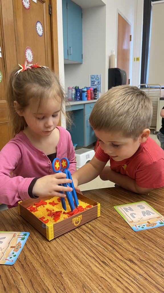 two students sitting at table manipulating objects in front of them