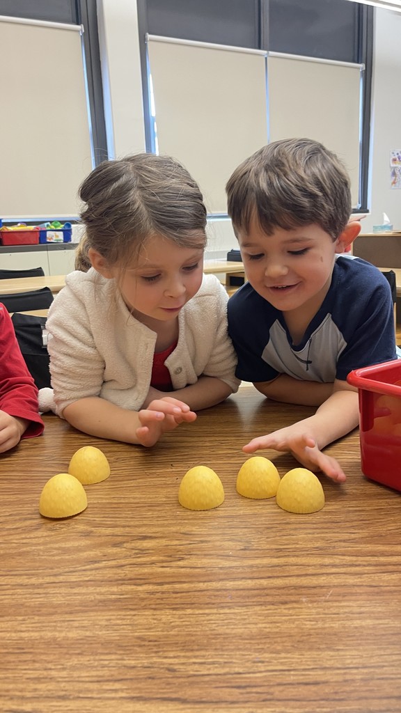 two students sitting at table manipulating objects in front of them