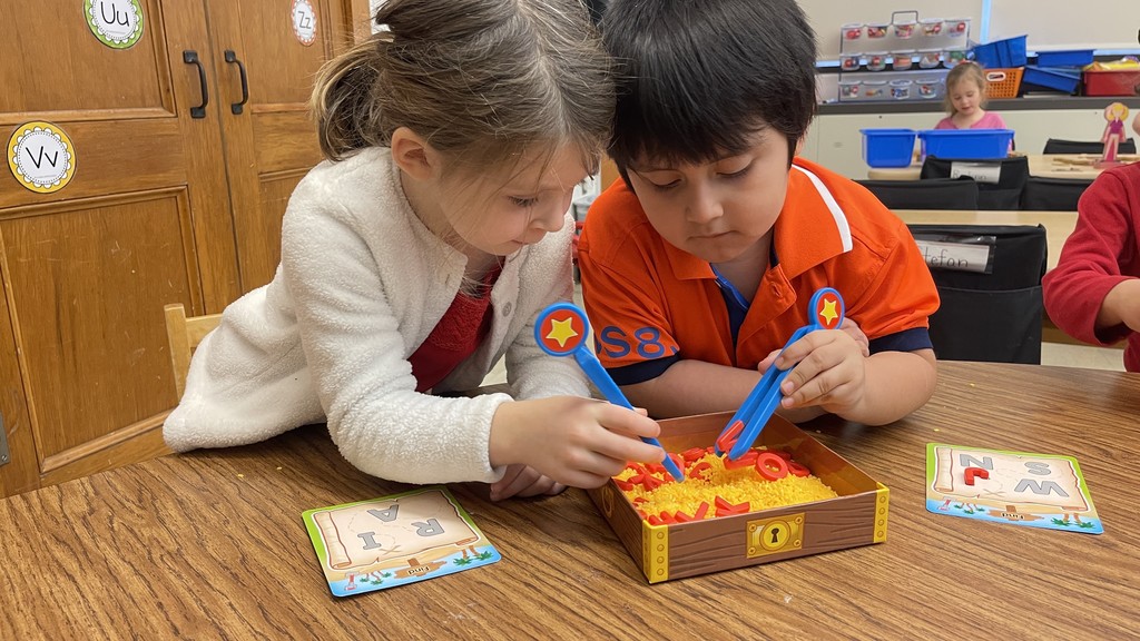 two students sitting at table manipulating objects in front of them