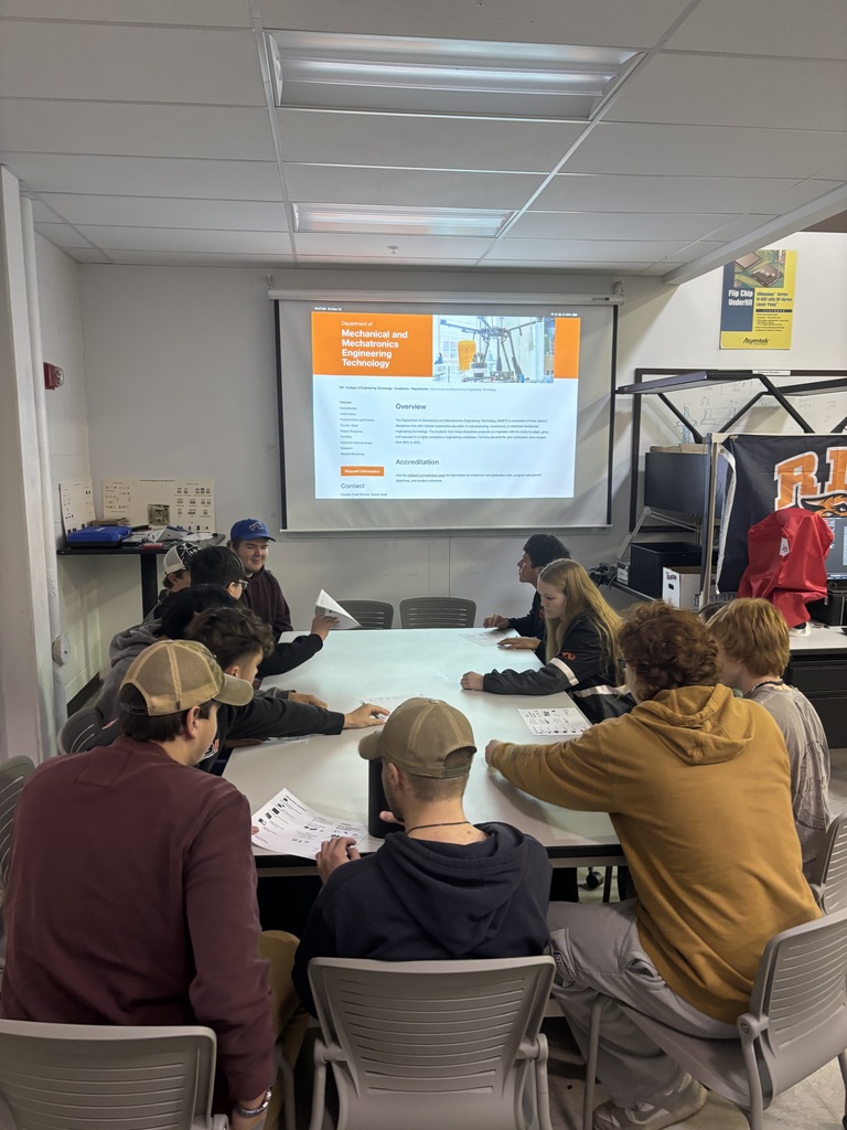 students gathered around a table listening to a presentation