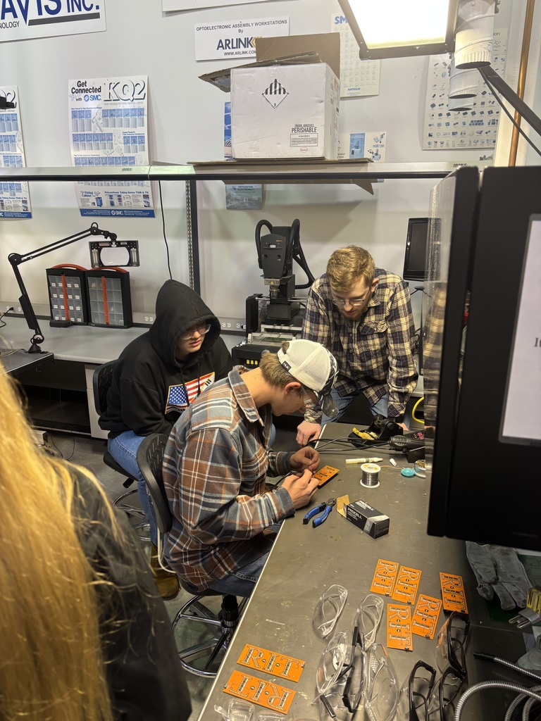 three students working on something on a workbench
