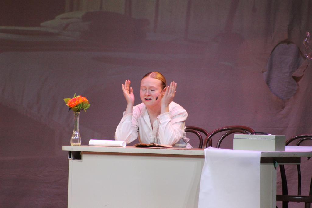 student sitting at desk on stage