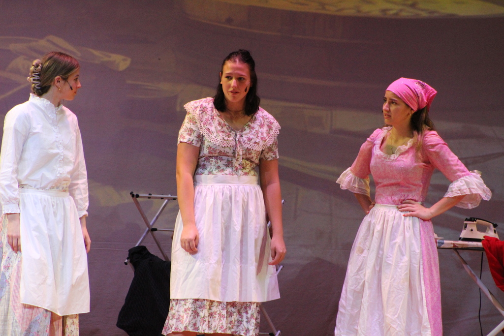 three students standing on stage