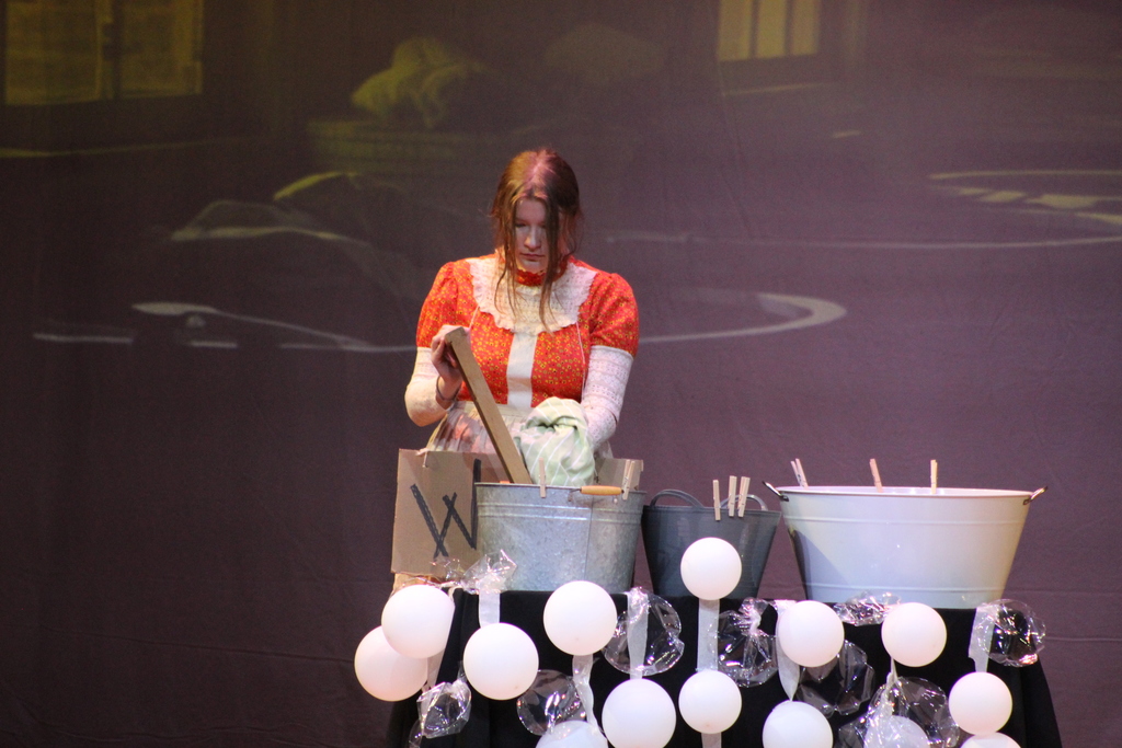 student washing laundry in tub on stage