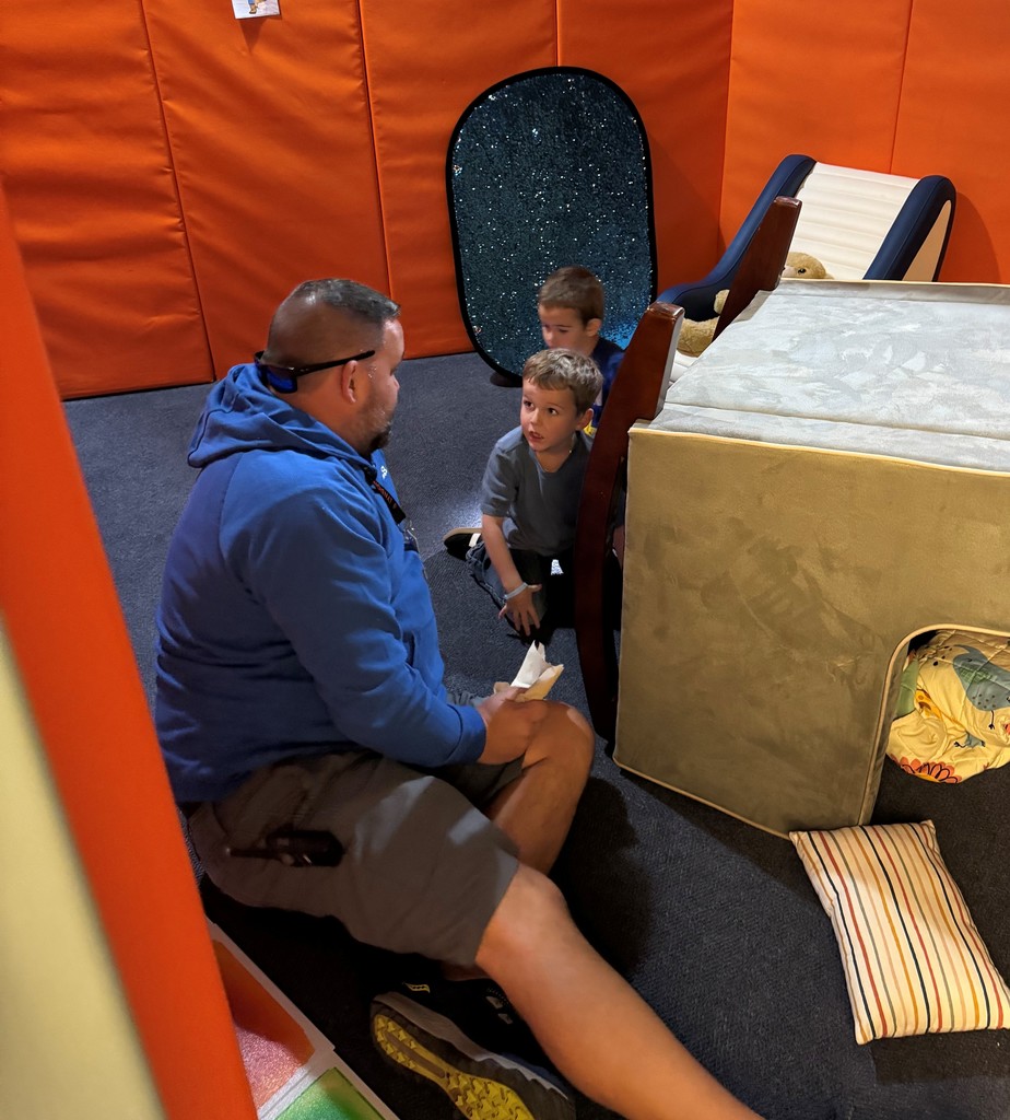 students talking to a staff member while they're all sitting on the floor