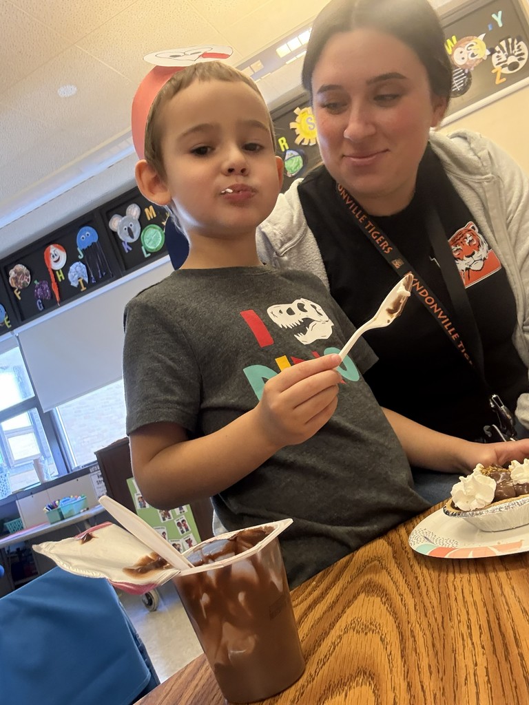 boy eating pie at table with adult nearby