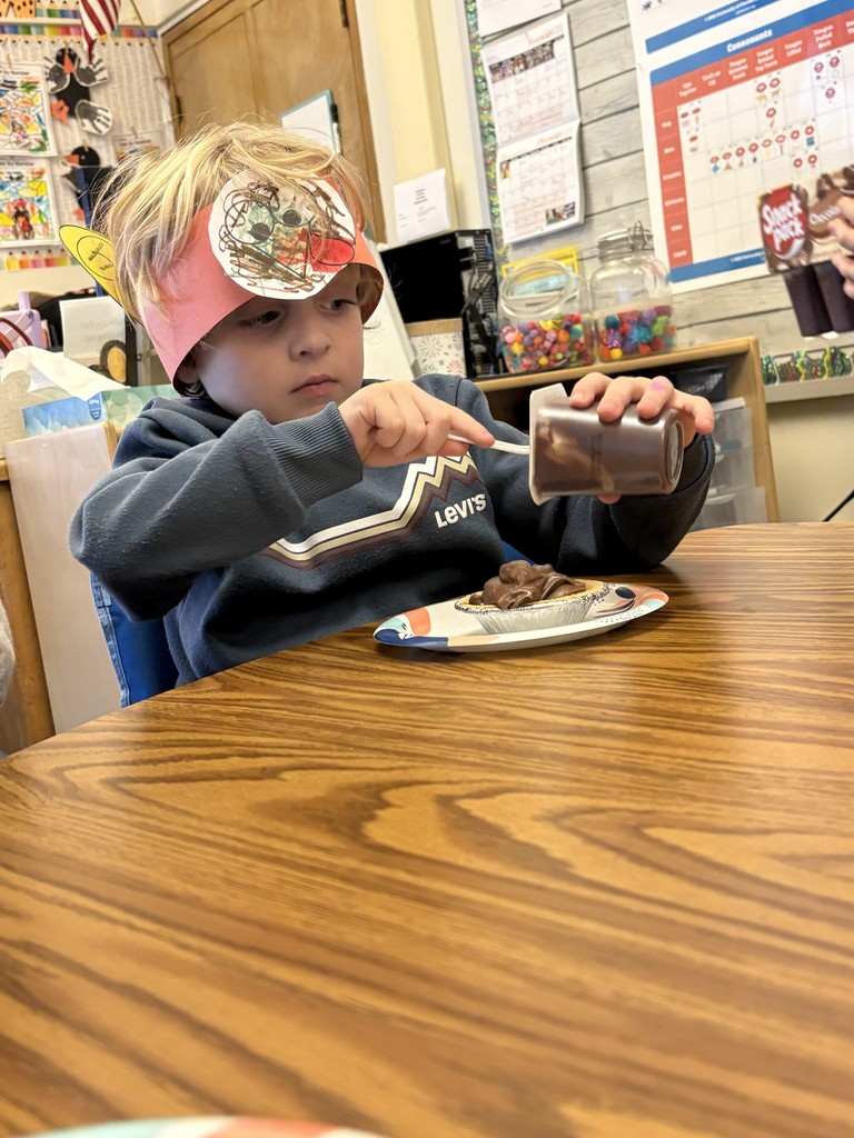 boy scraping pudding out of container into pie shell on table