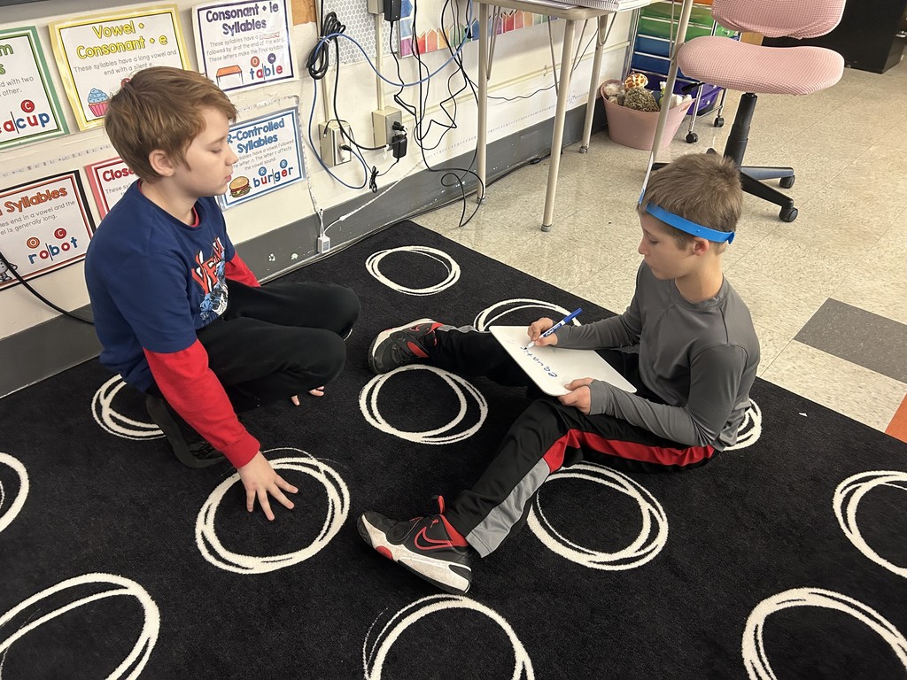 two boys sitting on the rug playing a game