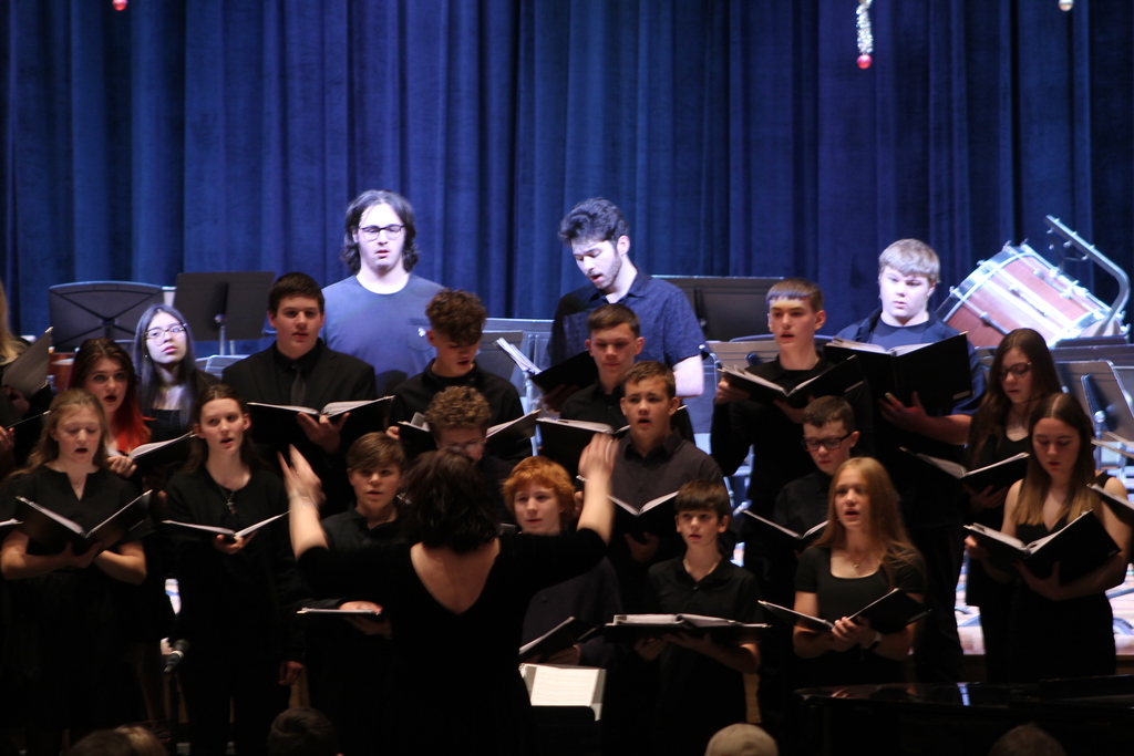 students holding choir books and singing on risers