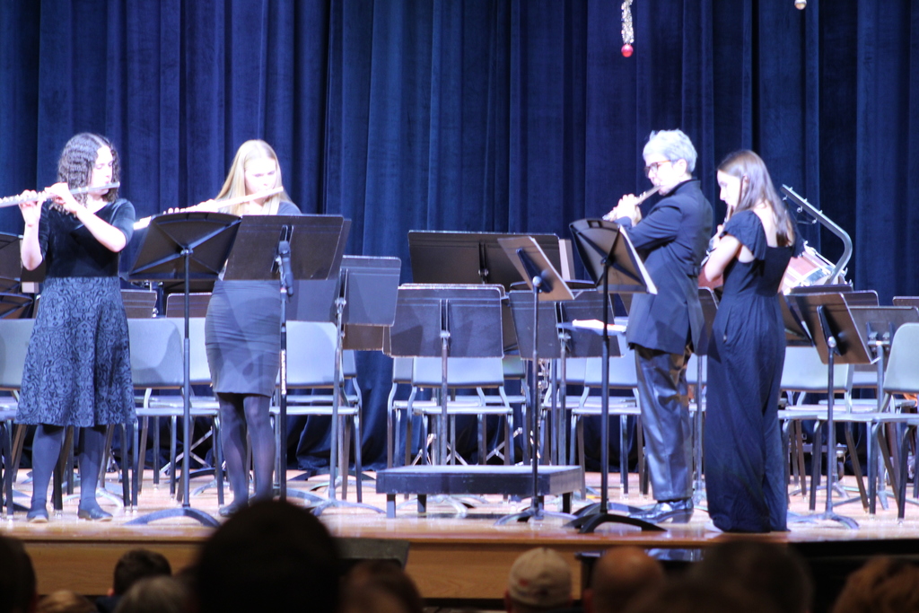students and teacher playing instruments in band on stage