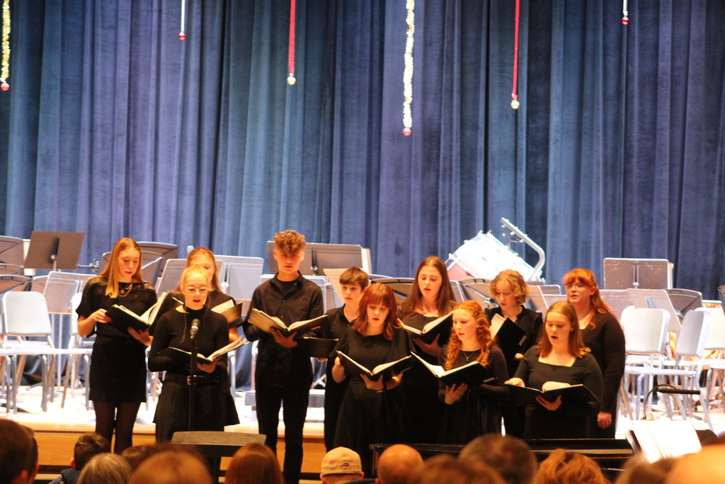 students holding choir books and singing on risers