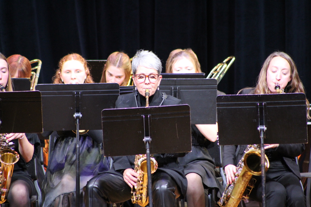 students and teachers playing instruments in band on stage