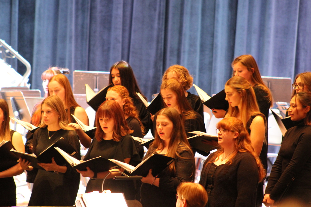 students holding choir books and singing on risers