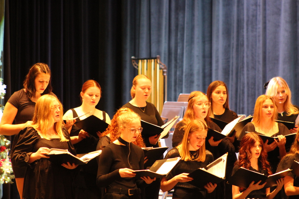 students holding choir books and singing on risers