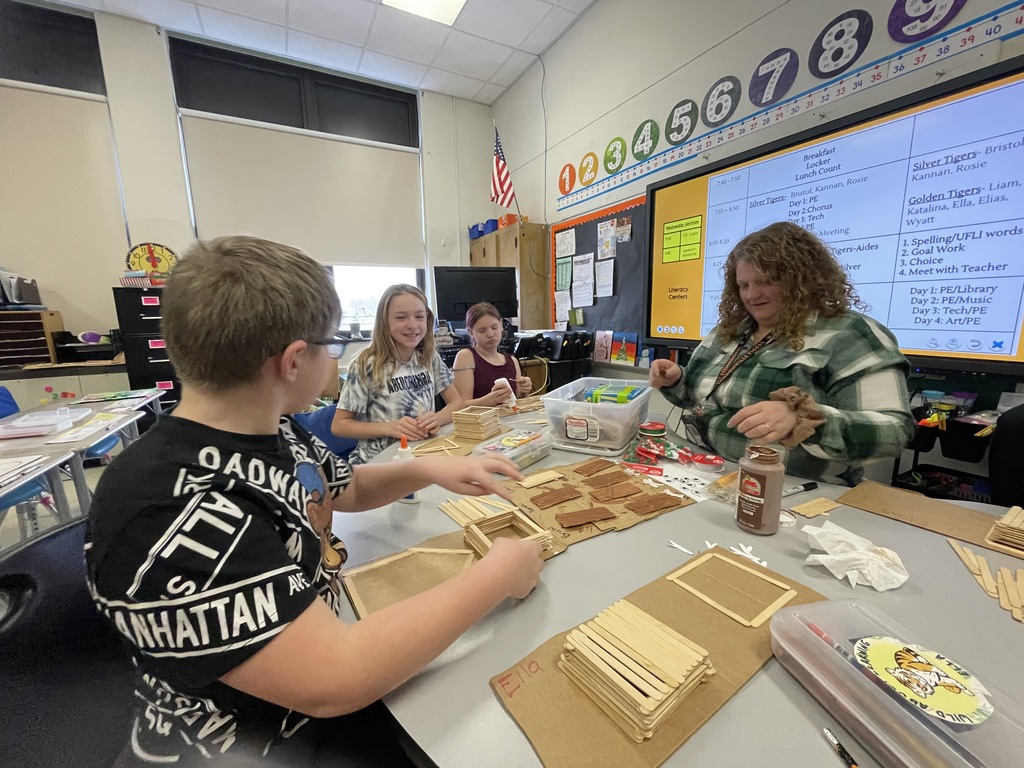 students working on a popsicle stick project with their teacher