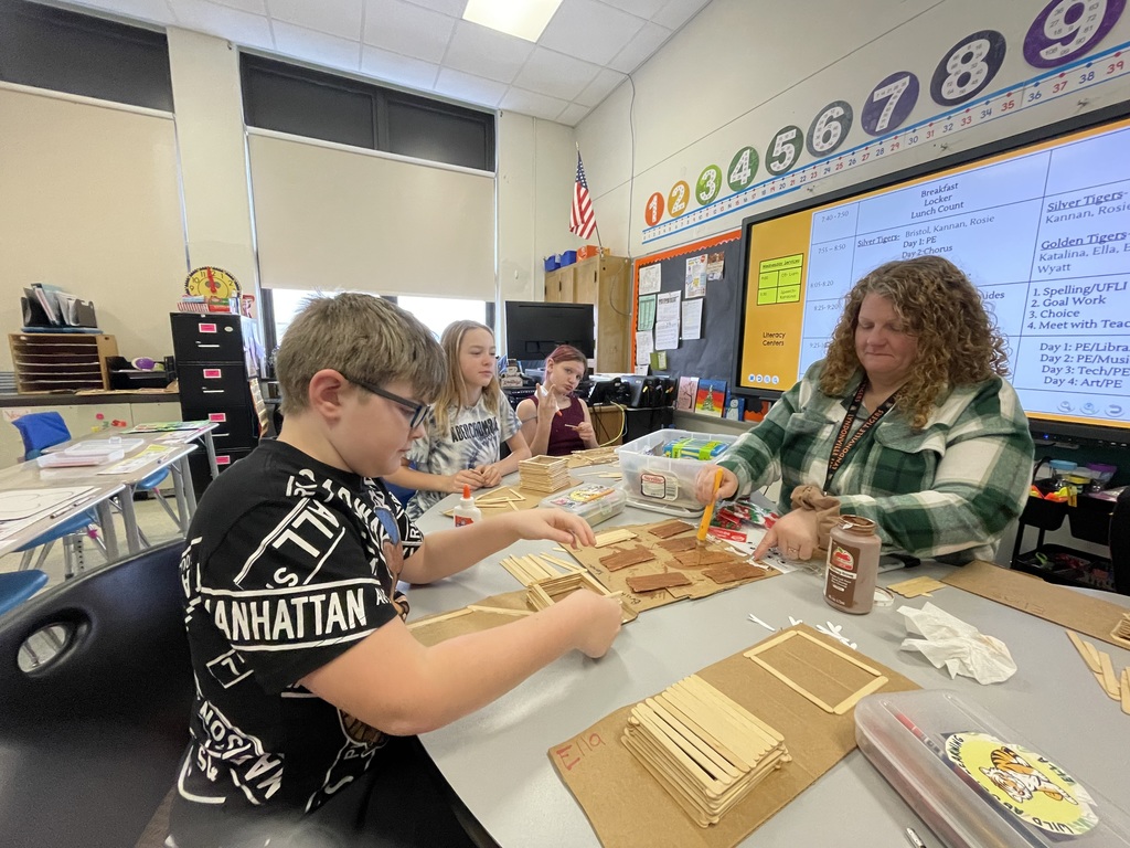 students working on a popsicle stick project with their teacher