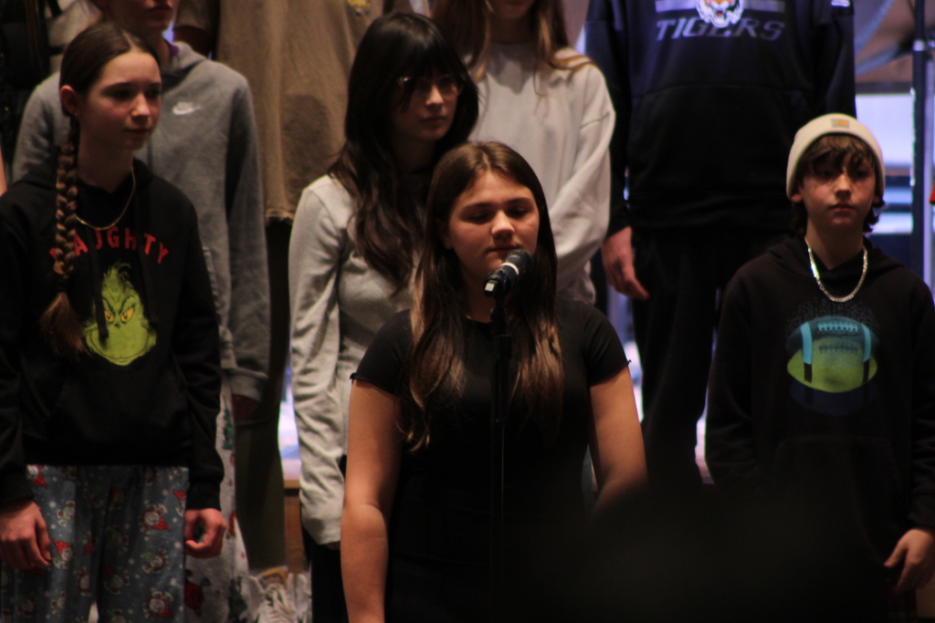 student singing a solo in front of students singing in choir on risers