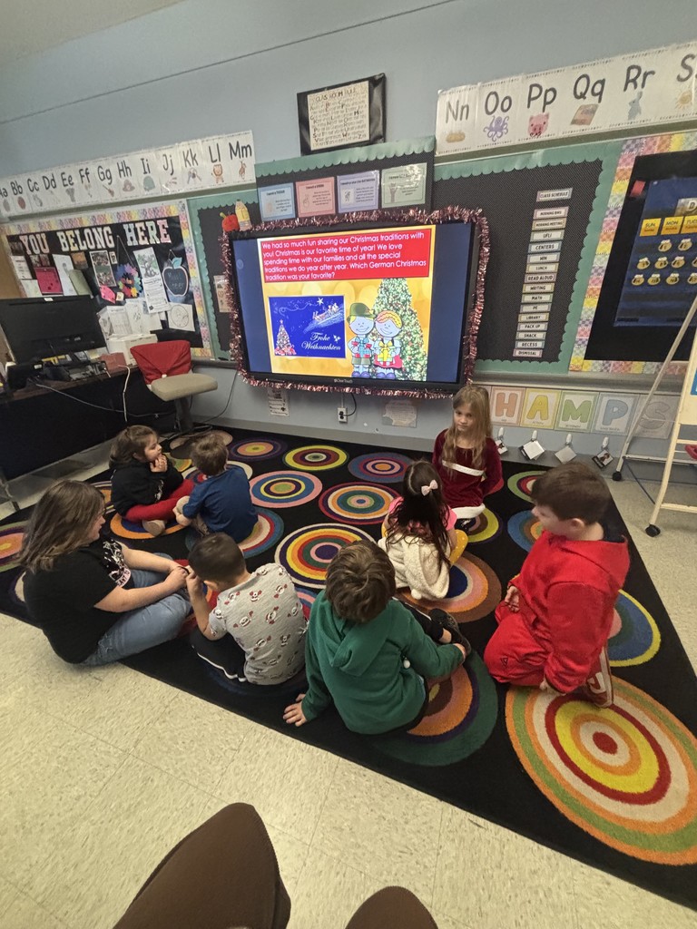 students listening on the carpet in classroom in front of smartboard