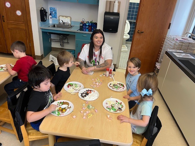 students and teacher sitting at tables working on gingerbread people