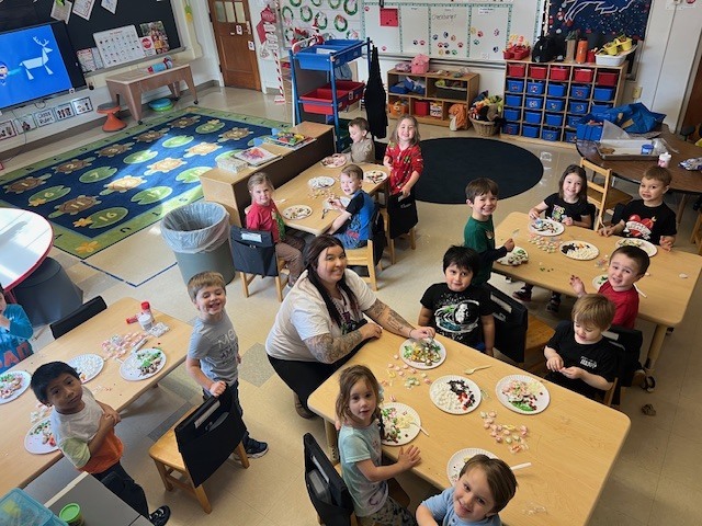 students and teacher sitting at tables working on gingerbread people