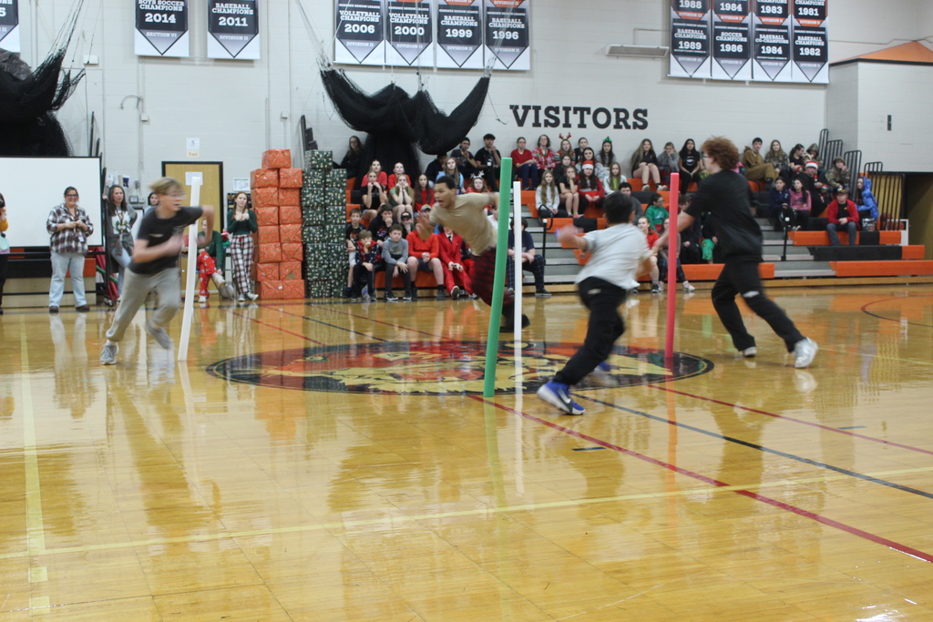 students chasing after pool noodles in gym