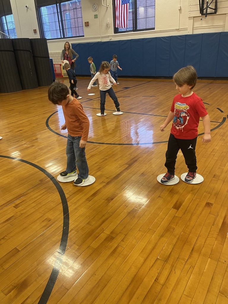 students standing on paper plates in gym