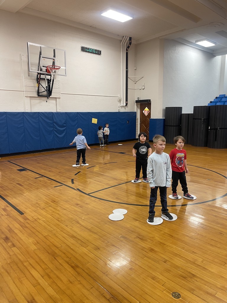 students standing on paper plates in gym