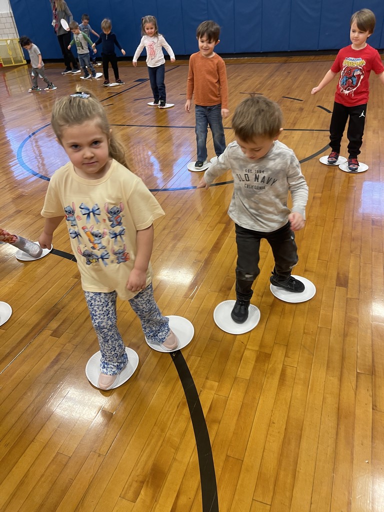 students standing on paper plates in gym