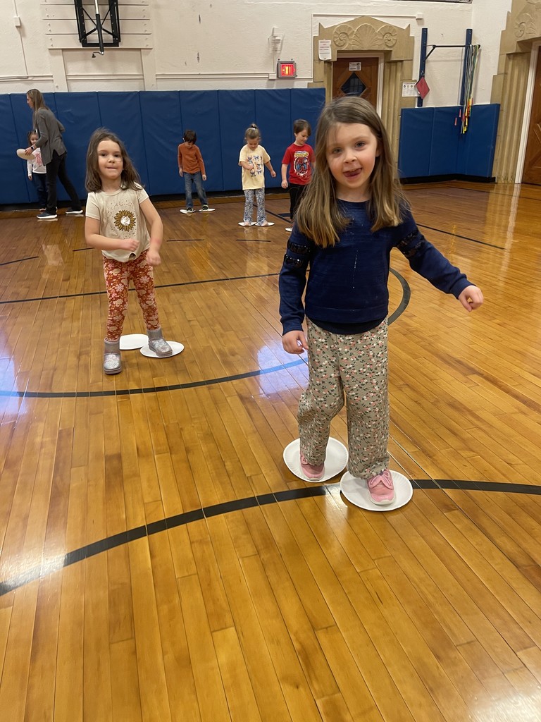 students standing on paper plates in gym