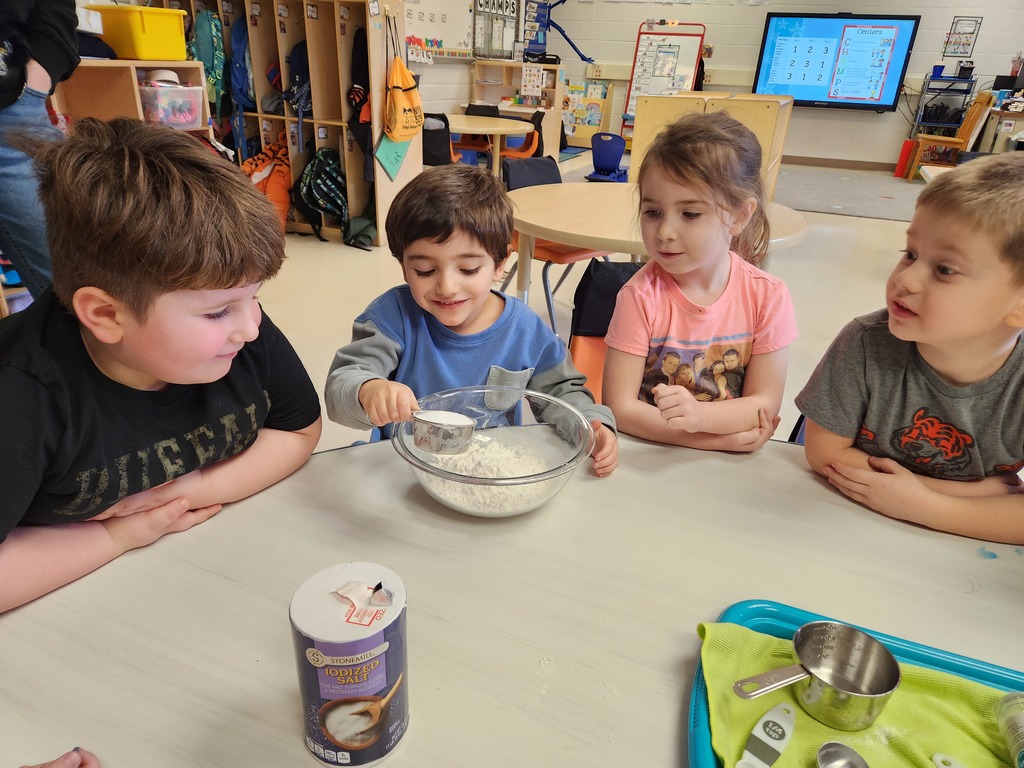 students sitting at table adding ingredients to a bowl