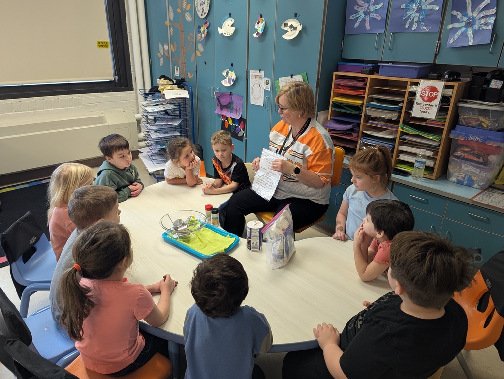 students sitting at table watching teacher