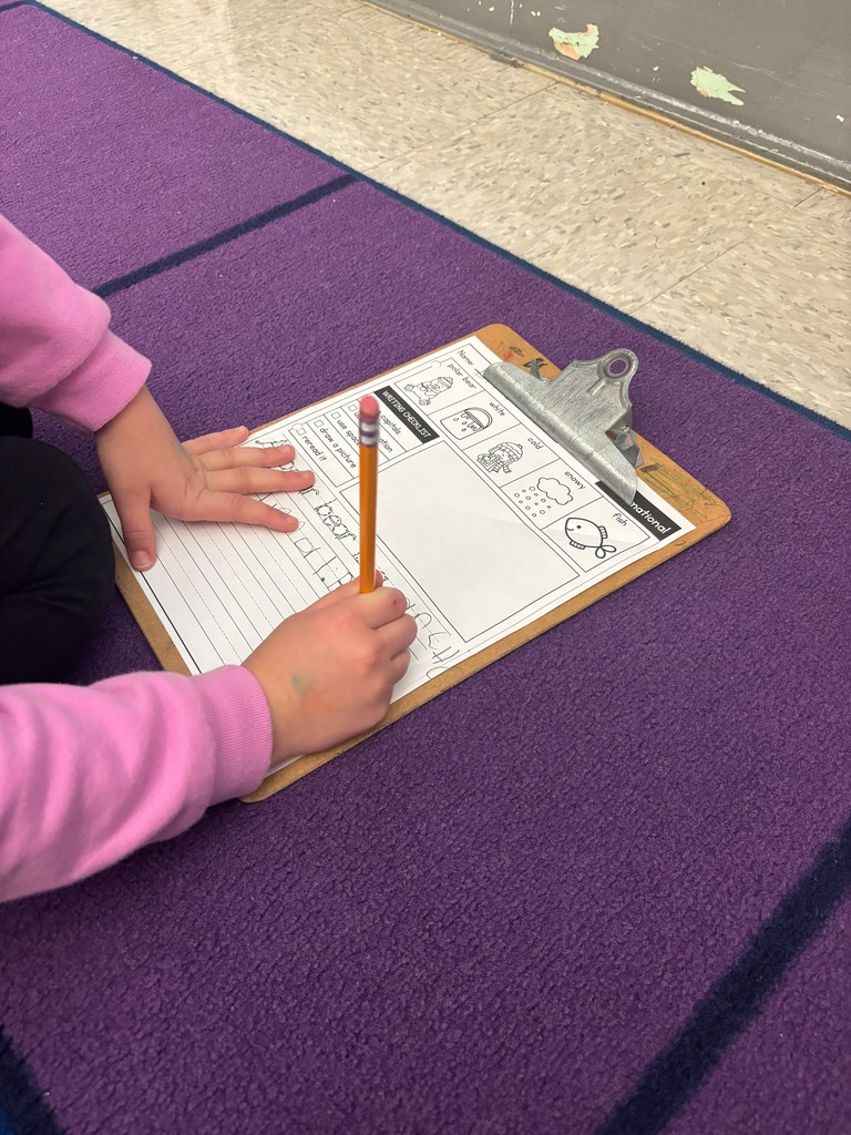 student writing on a worksheet on a clipboard