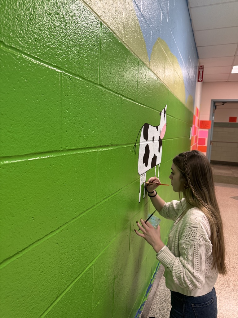 girl painting a cow on the wall