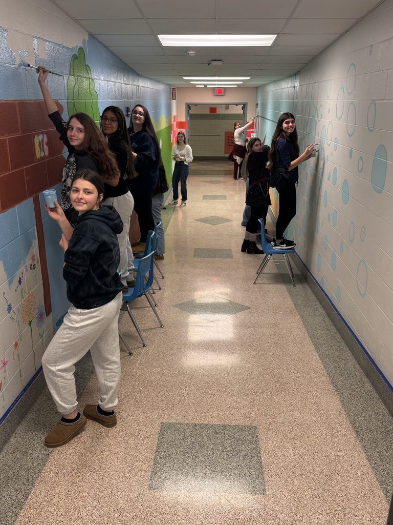 students painting murals on the walls in a hallway